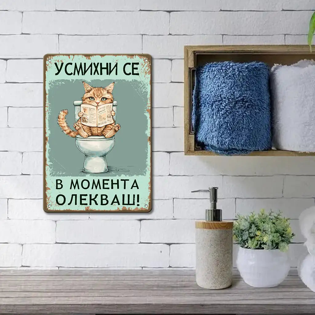 Табела за баня, изобразяваща пухкаво котенце, седнало върху тоалетната чиния и четящо вестник. Надписът над котенцето гласи "Усмихни се! В момента олекваш!"